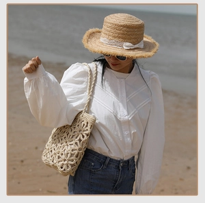 Detail of handcrafted woven shoulder bag with 3D floral crochet on sunny beach beach