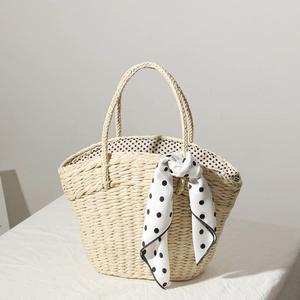 Detail of straw woven tote bag featuring a black and white polka dot silk scarf and lining