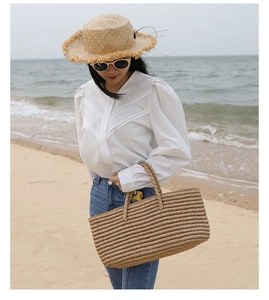 Handwoven straw tote bag and frayed sun hat shown on a beach for a summer holiday look