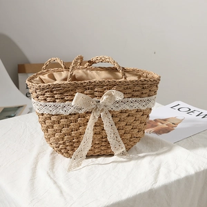 Handwoven straw tote bag with white lace bow and drawstring lining for beach vacations