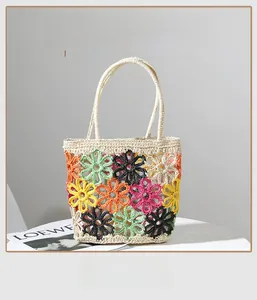 Detail der handgefertigten Strohtasche mit bunten Häkelblumen und gewebten Griffen