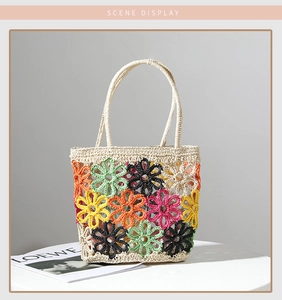 Detailansicht bunter Häkelblumenmuster auf einer sommerlichen Strandtasche aus Stroh