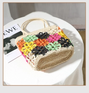Detailaufnahme bunter Häkelblumenmuster auf einer Stroh-Sommer-Strandtasche für Damen