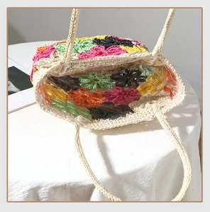 Detailansicht der handgefertigten Strohtasche mit bunten Häkelblumen und transparentem Futter