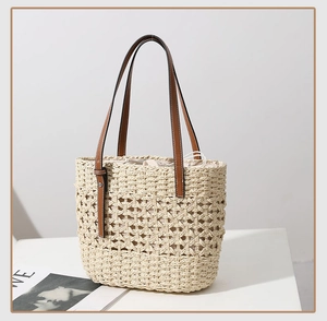 Detail of hollow woven straw tote bag featuring brown leather handles and drawstring liner