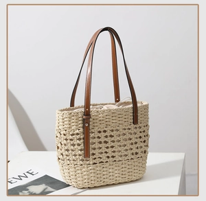 Detail of hollow woven straw tote featuring brown leather handles and inner drawstring bag