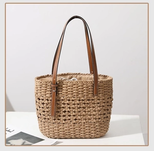 Detail view of handmade woven straw tote with brown leather handles and drawstring liner