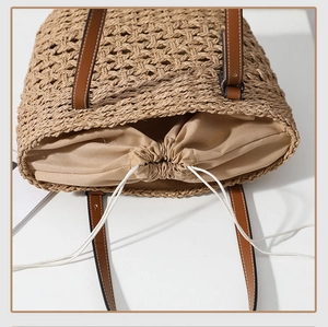 Detail of straw woven tote with drawstring lining and brown leather handles for beach