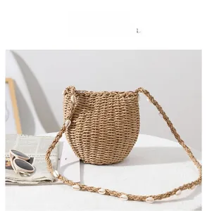 Dettaglio borsa a tracolla in paglia con decorazioni in conchiglia bianca sul cinturino