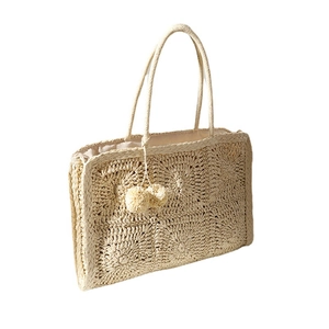 Borsa a spalla in paglia fatta a mano con pompon e motivi all'uncinetto su sfondo bianco