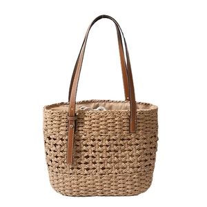 Handmade woven straw tote bag with leather handles and interior drawstring for beach vacation