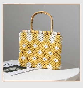 Detail of diamond weave pattern and natural bamboo handles on yellow woven tote bag