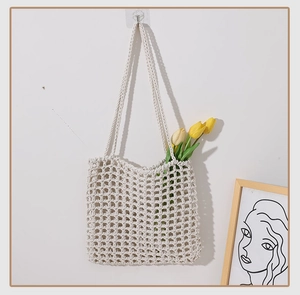 Close-up of cream woven mesh tote bag with flowers hanging in minimalist home setting