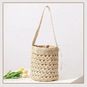 Detailed view of handmade straw bucket bag with hollow weave pattern and drawstring liner
