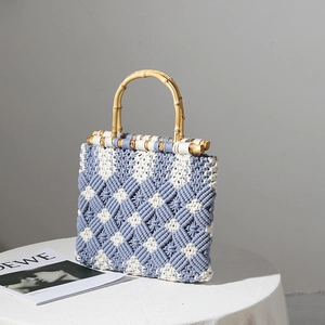Handmade blue and white macrame tote bag with natural bamboo handles on a table