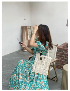 Détail d'un sac cabas en crochet blanc avec une robe mi-longue à fleurs et manches bouffantes