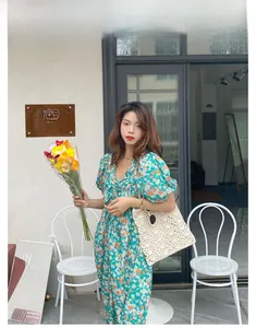 Détail du sac à bandoulière en paille crocheté à la main avec robe à fleurs vintage