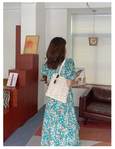Détail du sac à bandoulière tissé et robe verte à fleurs avec manches bouffantes