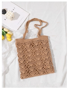 Détail d'un sac cabas marron tricoté à la main avec motif ajouré sur tissu blanc doux
