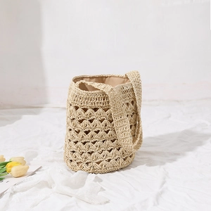 Handmade woven straw bucket bag with hollow pattern and tassel for beach vacations