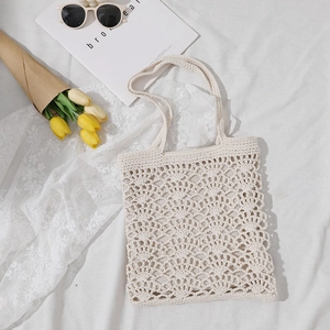 Sac cabas en crochet crème ajouré avec anses tressées sur tissu blanc avec des tulipes