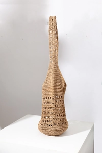 Detailed view of the hollow-out knit texture and natural straw weave of the shoulder bag