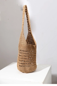 Close-up of hollow-out weave pattern on large natural straw shoulder bag for beach