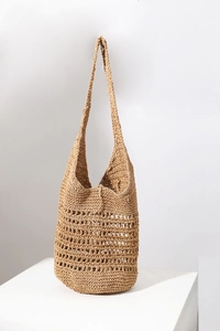 Detail of hollow-out handwoven straw tote bag with natural fiber texture on white stand