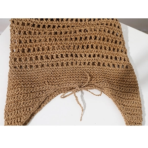 Close-up of brown hollow-out woven straw bag with a delicate decorative ribbon bow tie