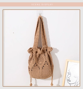 Detailed view of woven straw bucket bag with drawstring closure and floral crochet texture