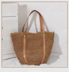 Detail of hand-woven straw tote bag featuring brown leather handles and metal rivets