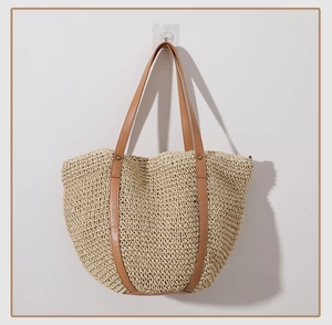 Close-up of fine straw weave texture and brown leather straps with metal rivets on beach bag