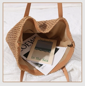 Top view of large straw tote bag with brown leather handles and inner pocket detail