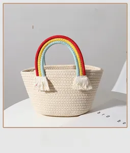Detail of hand-woven cotton rope bag with rainbow handles and decorative white tassels