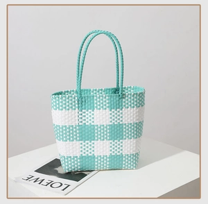 Detail of green and white checkered woven tote bag with slim handles for summer beach