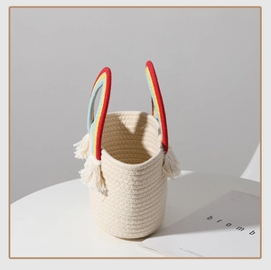 Detail of handmade cotton rope basket featuring rainbow handles and white tassel accents