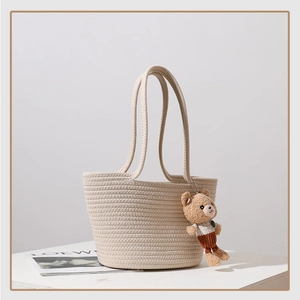 Detailed texture of woven cotton rope beach bag with a cute bear pendant and long handles