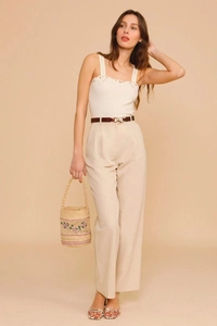 Detail of raffia bucket bag with floral embroidery and woman in summer knit vest