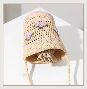 Close-up of hand-woven raffia bag with purple crochet flower embroidery and drawstring liner