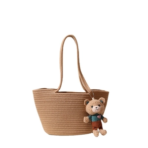 Brown woven straw tote bag with long handles and a cute teddy bear charm pendant