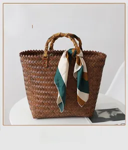 Detail of brown woven tote bag with bamboo handle and elegant green silk scarf decoration
