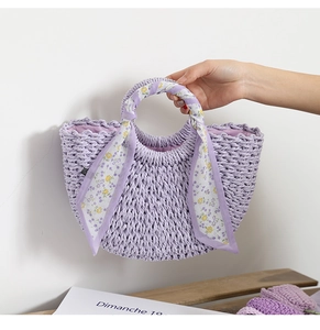 Detail of lavender woven handbag featuring floral silk scarf handle and crescent shape