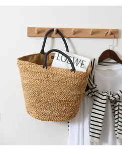 Detail of hand-woven straw tote bag with black rope handles and brown fabric lining