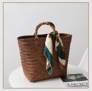 Detail of woven brown leather tote with bamboo handle and colorful silk scarf accessory