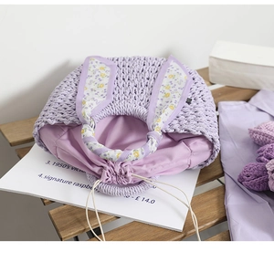 Detail of lavender crochet bucket bag with floral ribbon handle on a wooden bench
