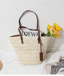 Détail du cabas en paille tressée à la main avec anses en cuir marron et foulard chic