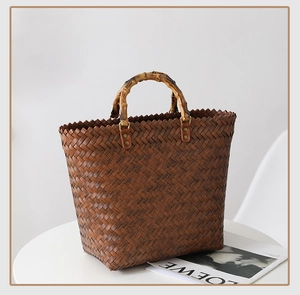 Detailed view of woven leather texture and bamboo handle on a dark brown tote bag