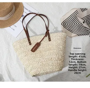 Détail d'un sac cabas en paille tressée à la main avec anses en cuir et rivets