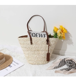 Détail du sac en paille tressée avec anses en cuir marron foncé et texture naturelle