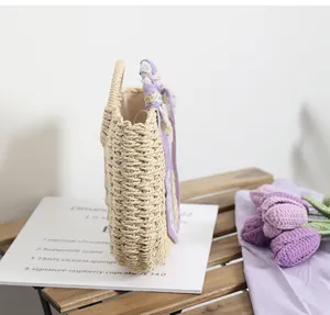 Detail of straw handbag with purple floral silk scarf on wooden tabletop background